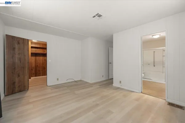 a view of an empty room with closet and a window