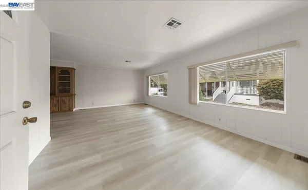 a view of an empty room with window and wooden floor