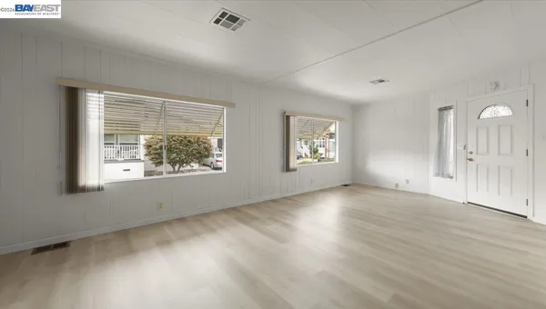 an empty room with wooden floor and windows