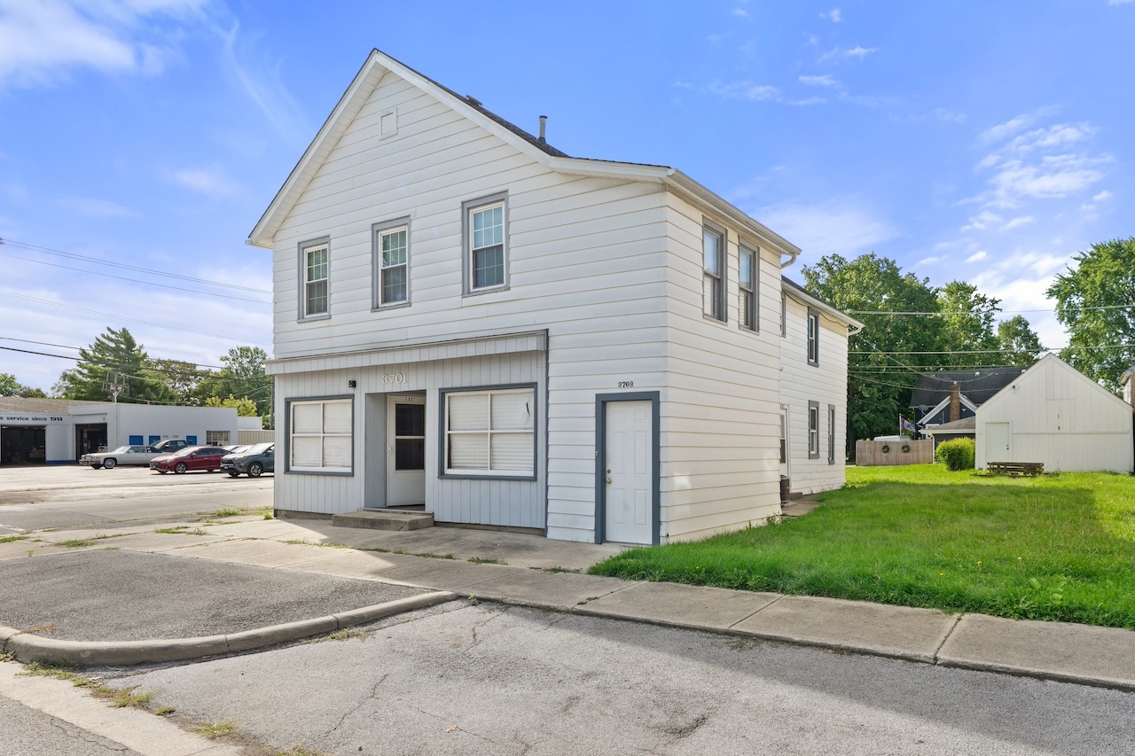 a view of a white house with a yard and plants