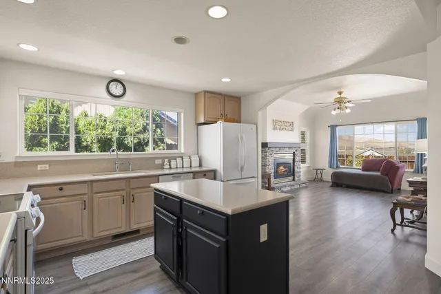 a kitchen with sink refrigerator and couches with wooden floor