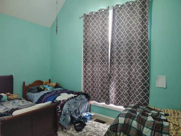 a bed sitting in a bedroom next to a window with wooden floor