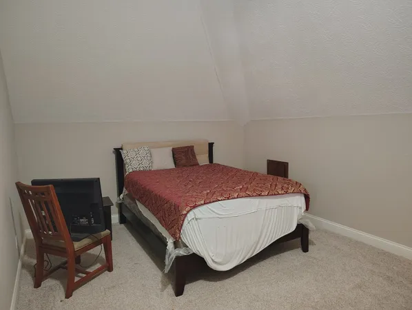 a spacious bedroom with a bed and chair