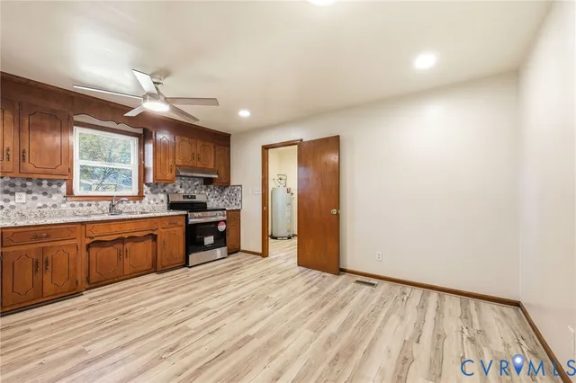 a kitchen with stainless steel appliances granite countertop a refrigerator a sink dishwasher a stove with wooden cabinets and floor