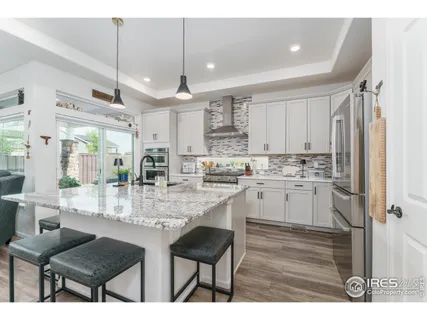 a kitchen with kitchen island granite countertop a table chairs sink and cabinets