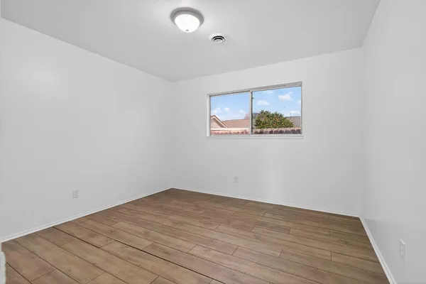 a view of empty room with wooden floor