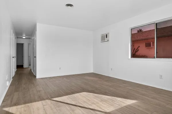 a view of an empty room with wooden floor and a window