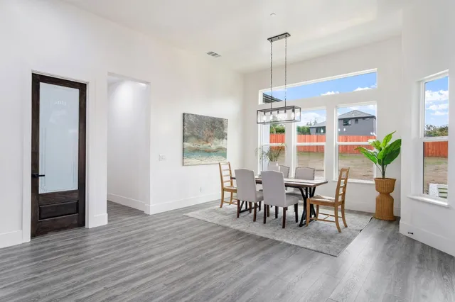 a view of a dining room and livingroom with furniture wooden floor a chandelier
