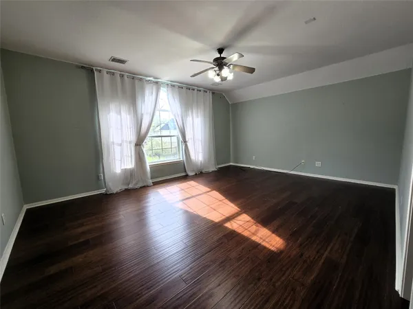 an empty room with wooden floor and windows