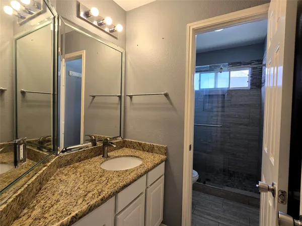 a bathroom with a granite countertop sink and a mirror