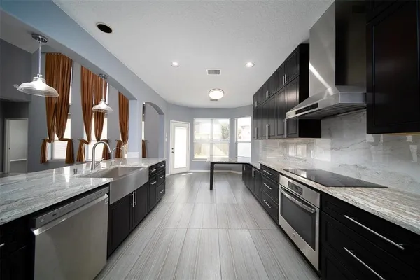 a large kitchen with stainless steel appliances granite countertop a lot of counter space and wooden floor