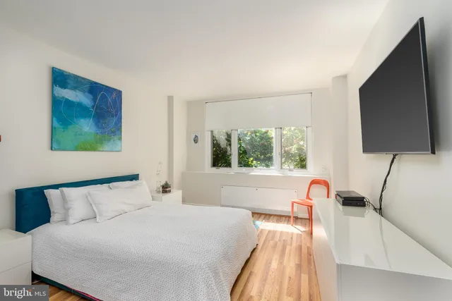a bedroom with a bed and a flat tv screen on the dresser