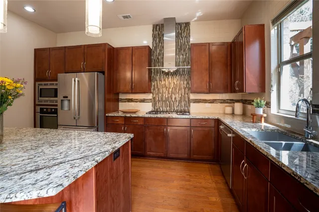 a kitchen with stainless steel appliances kitchen island granite countertop a refrigerator and a stove top oven