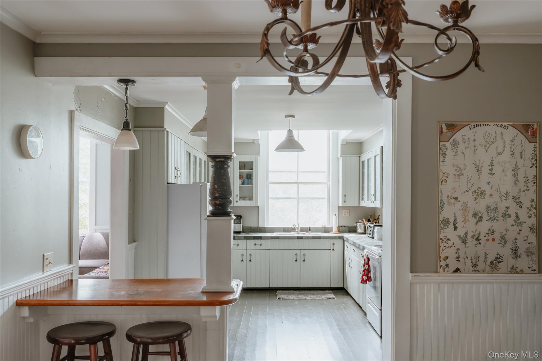 48 Upper Main Street Callicoon, NY 12723 - Photo 36 of 48 Kitchen with a wainscoted wall, ornamental molding, white cabinets, a kitchen bar, and hanging light fixtures