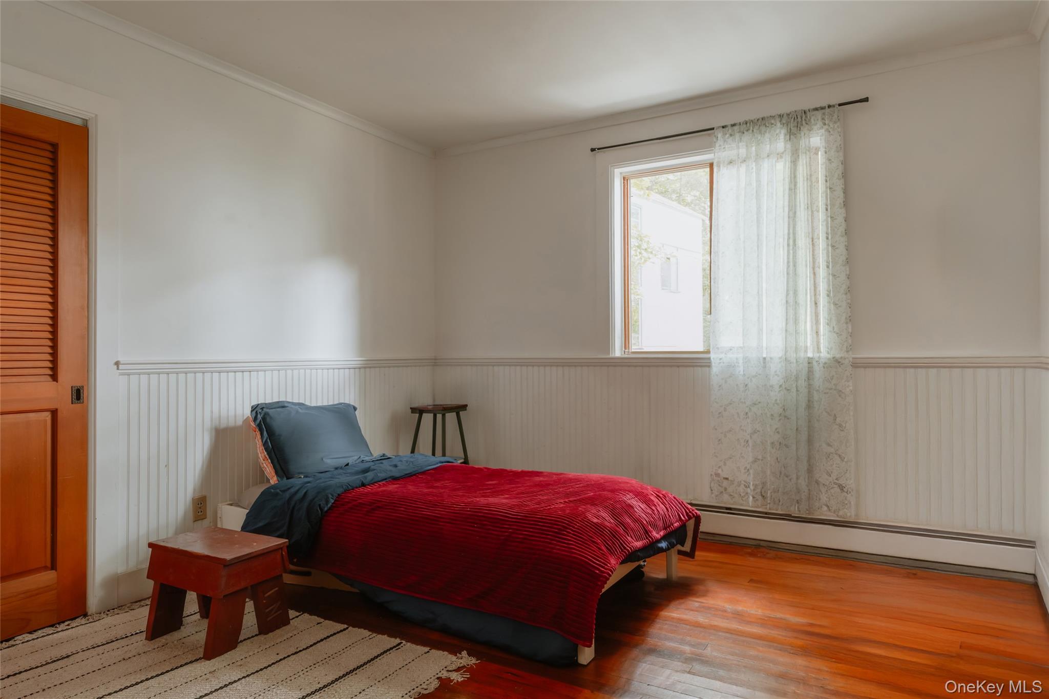 48 Upper Main Street Callicoon, NY 12723 - Photo 39 of 48 Bedroom featuring wood finished floors, a baseboard heating unit, crown molding, and wainscoting