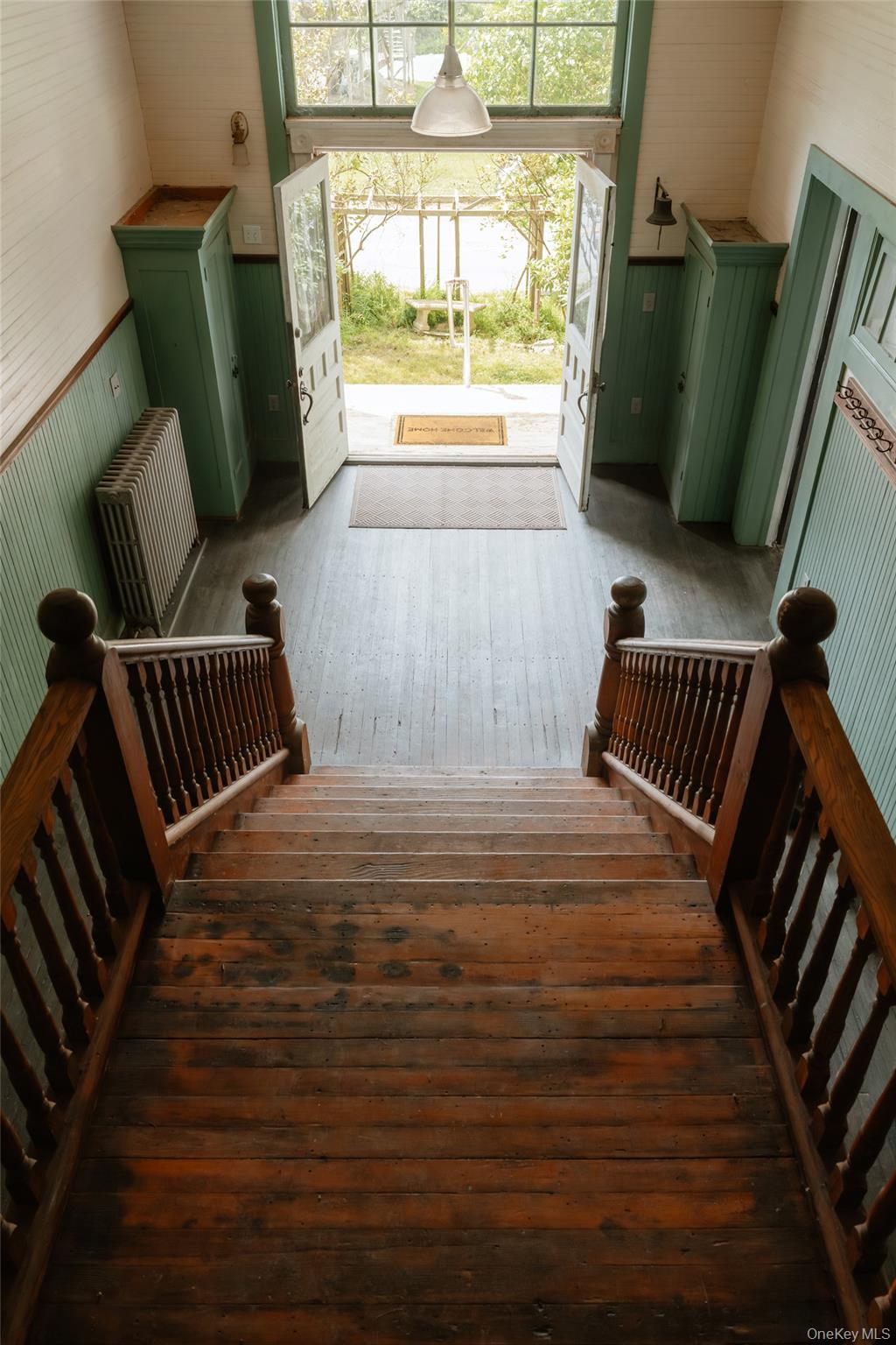 48 Upper Main Street Callicoon, NY 12723 - Photo 7 of 48 Stairs featuring hardwood / wood-style floors, wooden walls, radiator heating unit, and wainscoting