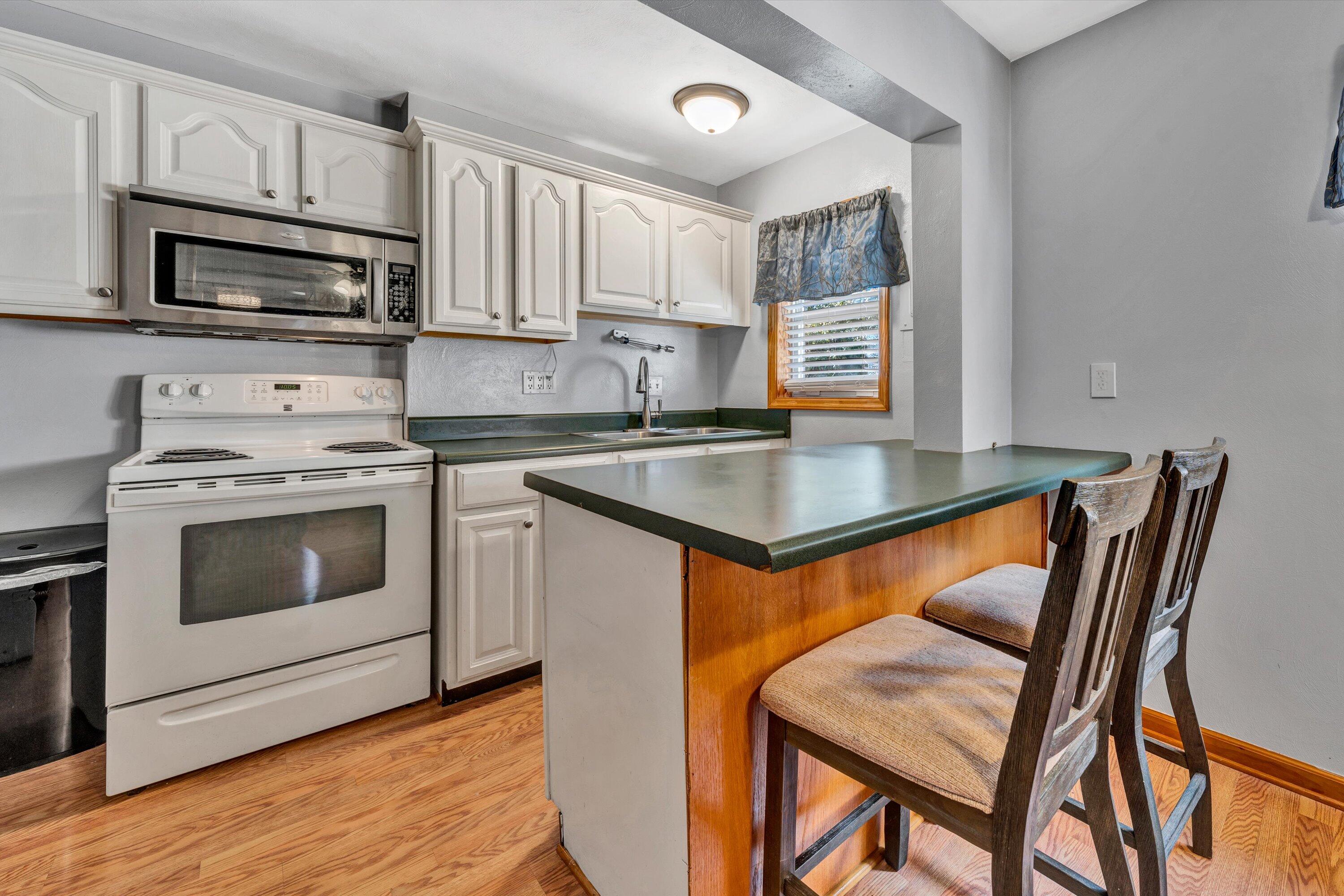 1120 Turner Branch Road Goodview, VA 24095 - Photo 11 of 35 a kitchen with stainless steel appliances granite countertop a stove a microwave a sink and white cabinets