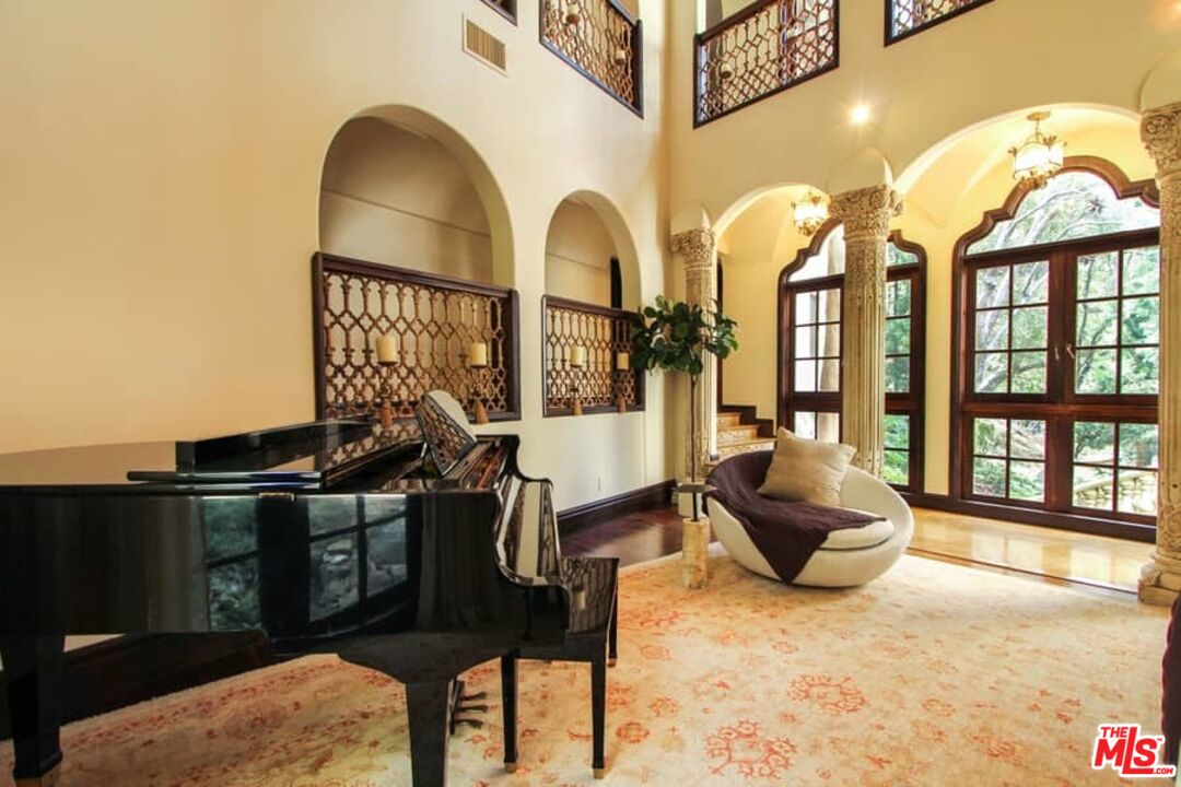 1016 Moraga Drive Los Angeles, CA 90049 - Photo 8 of 30 a living room with furniture a fireplace and floor to ceiling windows