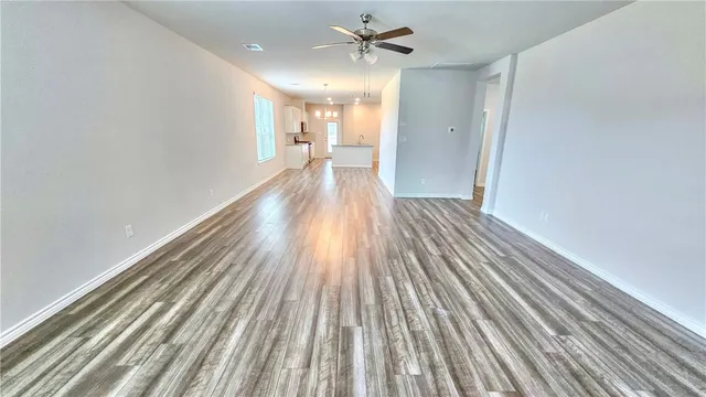 a view of a room with wooden floor a ceiling fan and staircase