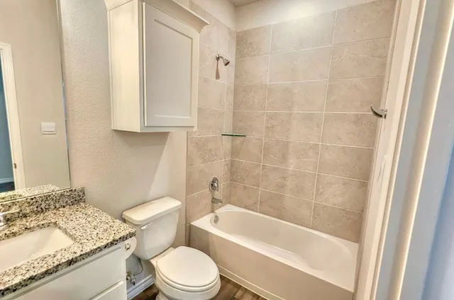 a bathroom with a granite countertop toilet a sink and bathtub