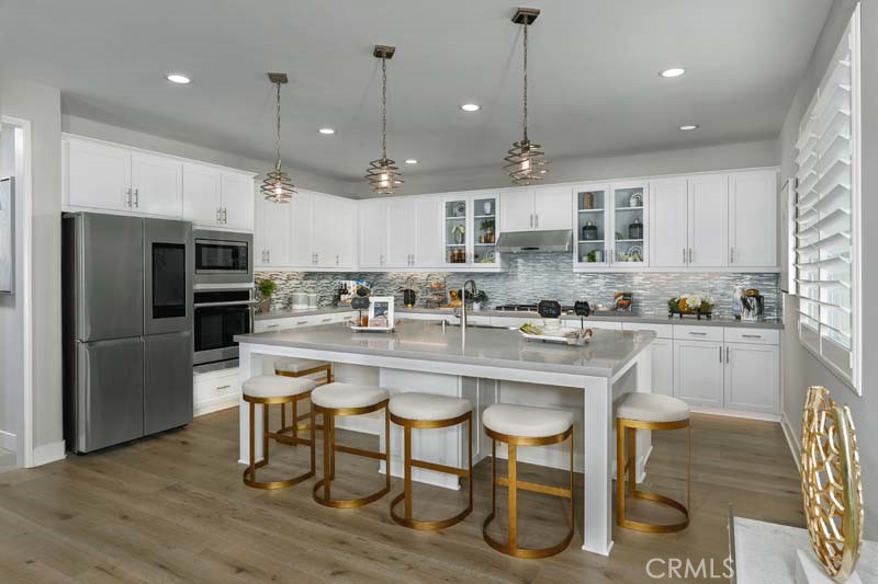 38924 Malva Rosa Drive Palmdale, CA 93551 - Photo 8 of 25 a kitchen with stainless steel appliances granite countertop a sink a stove a refrigerator and a dining table with wooden floor