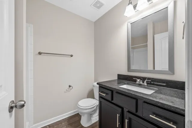 a bathroom with a granite countertop sink toilet and mirror
