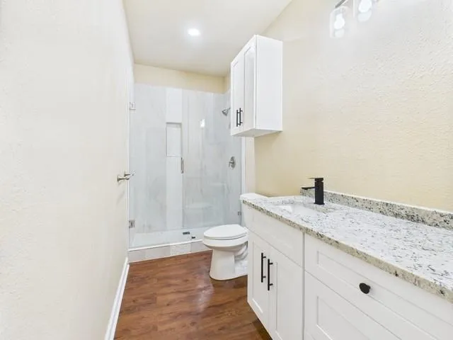 a bathroom with a granite countertop sink a toilet and a shower