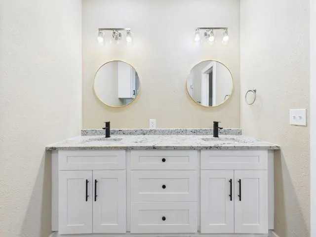 a bathroom with a granite countertop double vanity sinks and a mirror