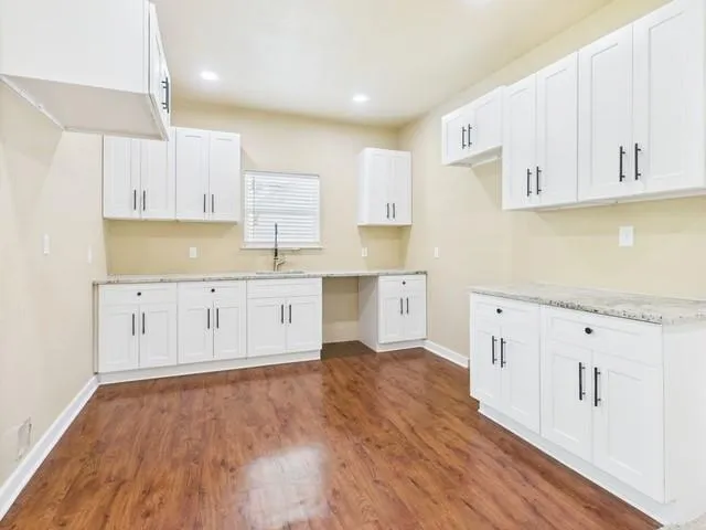 a view of an empty room with wooden floor and a ceiling fan