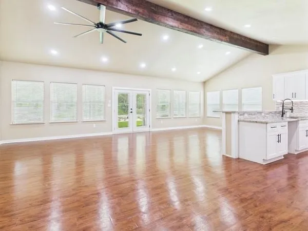 a view of an empty room with window and wooden floor