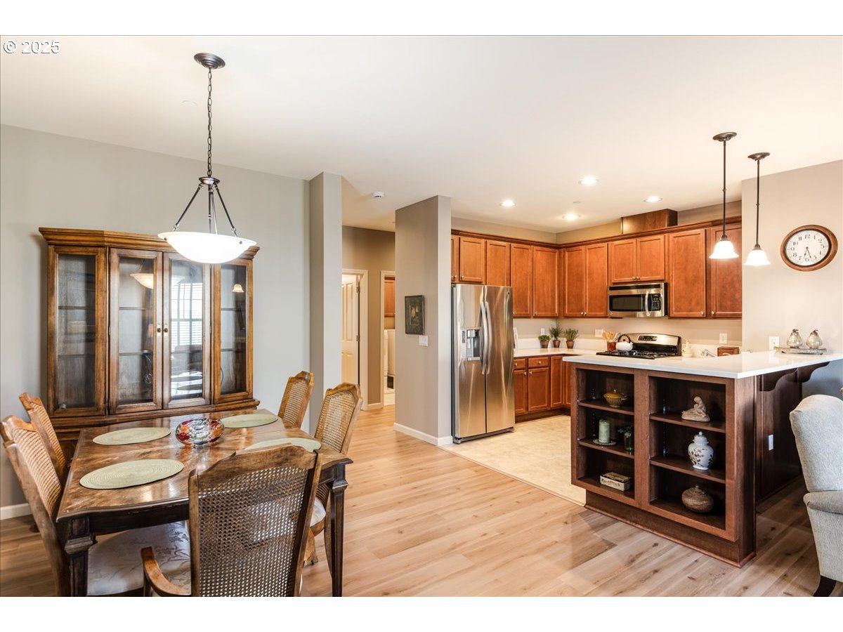 1258 Northwest Shattuck Way, Unit 309 Gresham, OR 97030 - Photo 15 of 33 a room with stainless steel appliances kitchen island granite countertop a dining table chairs and a refrigerator