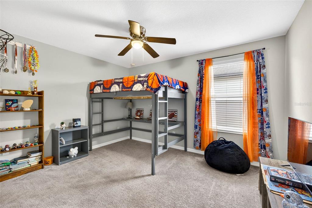 9616 Lemon Drop Loop Sun City Center, FL 33573 - Photo 35 of 53 a bedroom with a bed and a chandelier