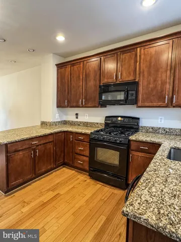 a kitchen with stainless steel appliances granite countertop wooden cabinets a stove top oven a sink and dishwasher