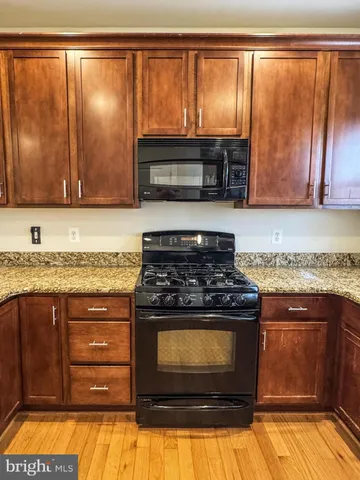a kitchen with granite countertop a stove top oven cabinetry and a granite counter top