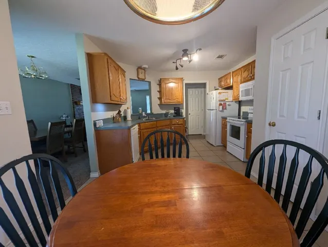 a kitchen with sink refrigerator dining table and chairs