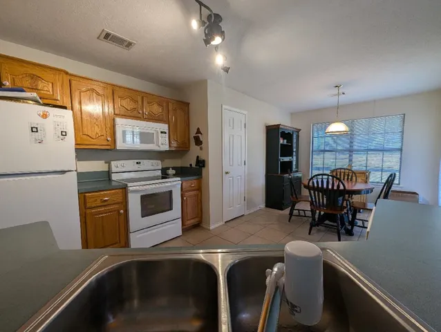 a kitchen with stainless steel appliances granite countertop a stove top oven a refrigerator a dining table and chairs with wooden floor