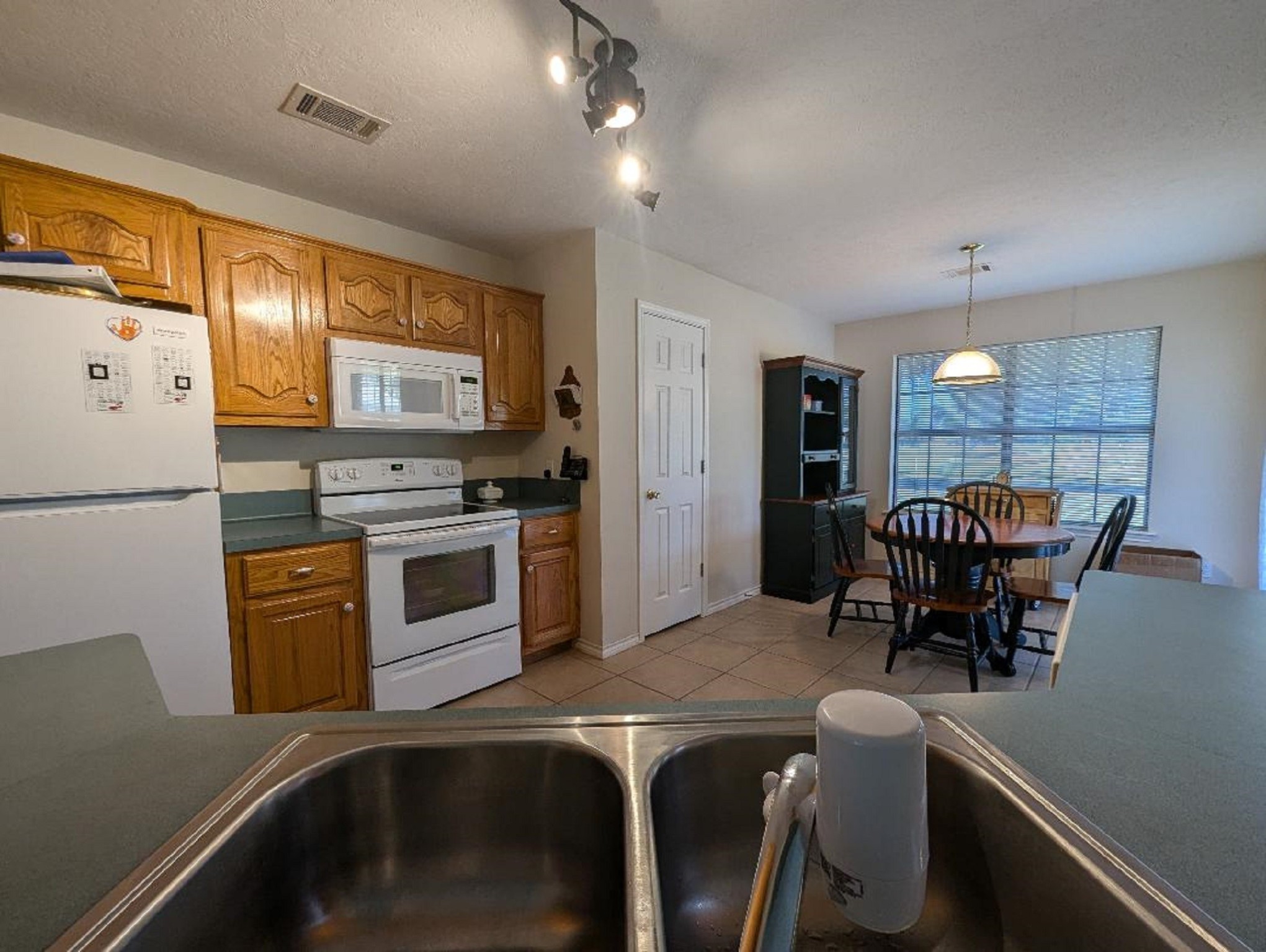 141 Coral Gables Trinity, TX 75862 - Photo 20 of 42 a kitchen with stainless steel appliances granite countertop a stove top oven a refrigerator a dining table and chairs with wooden floor