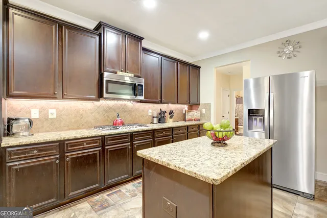 a kitchen with stainless steel appliances granite countertop a sink refrigerator and cabinets