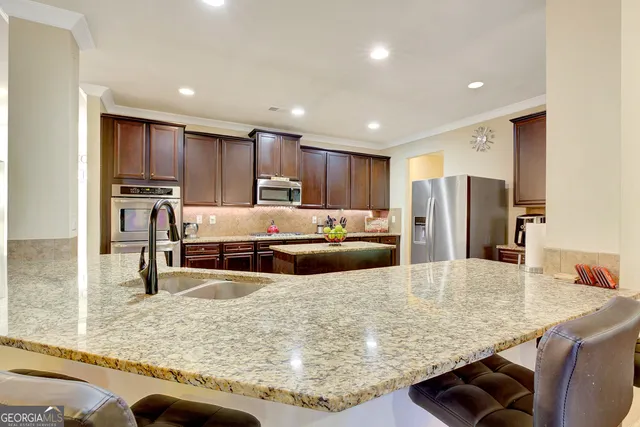 a kitchen with stainless steel appliances granite countertop a sink refrigerator and cabinets