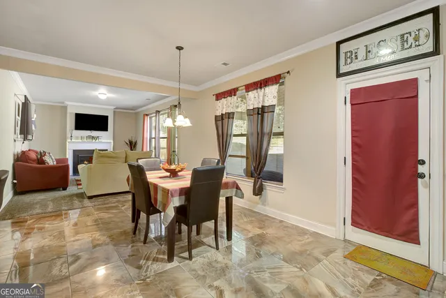 a view of a dining room and livingroom with furniture wooden floor a rug a flat screen tv a painting and a chandelier
