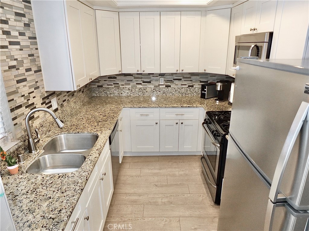 117 West Spring Street, Unit E Long Beach, CA 90806 - Photo 11 of 44 a kitchen with granite countertop a sink a stove top oven and cabinetry