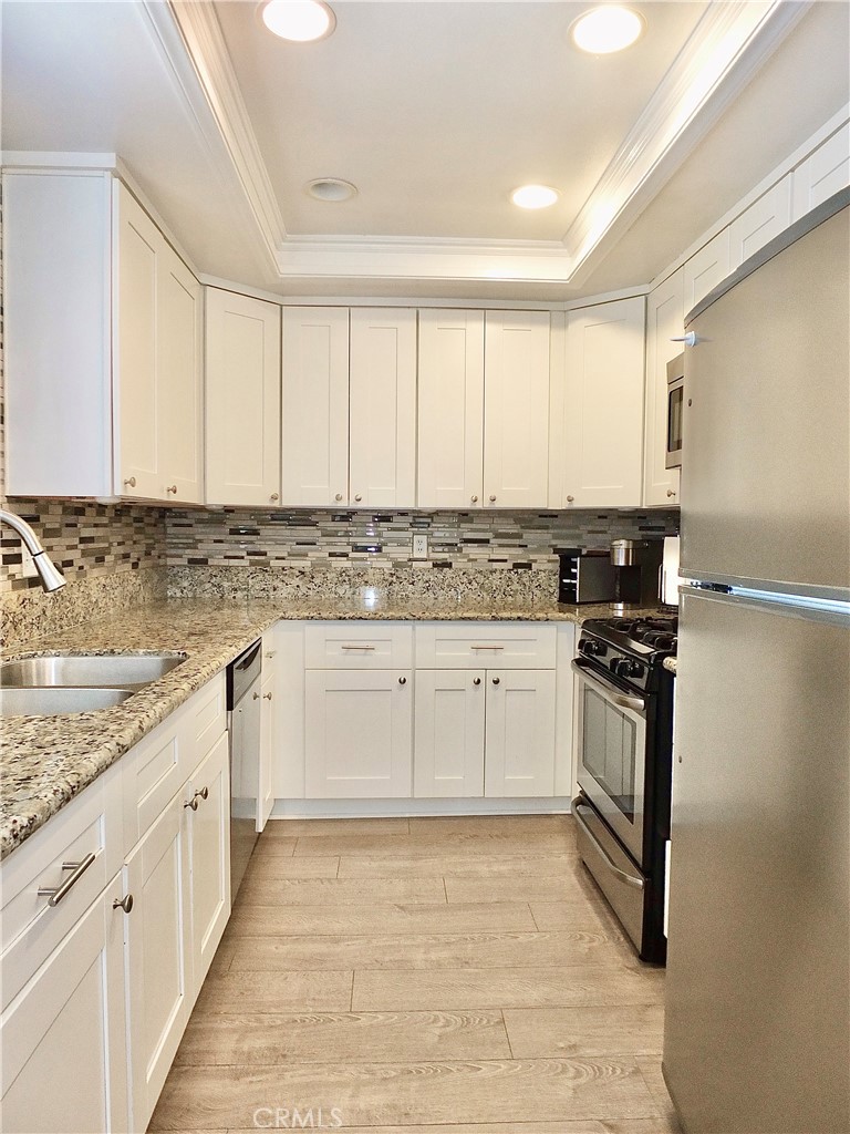 117 West Spring Street, Unit E Long Beach, CA 90806 - Photo 12 of 44 a kitchen with granite countertop white cabinets and stainless steel appliances