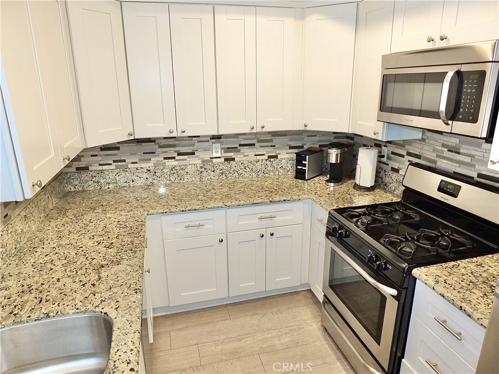 117 West Spring Street, Unit E Long Beach, CA 90806 - Photo 13 of 44 a kitchen with granite countertop white cabinets and stainless steel appliances
