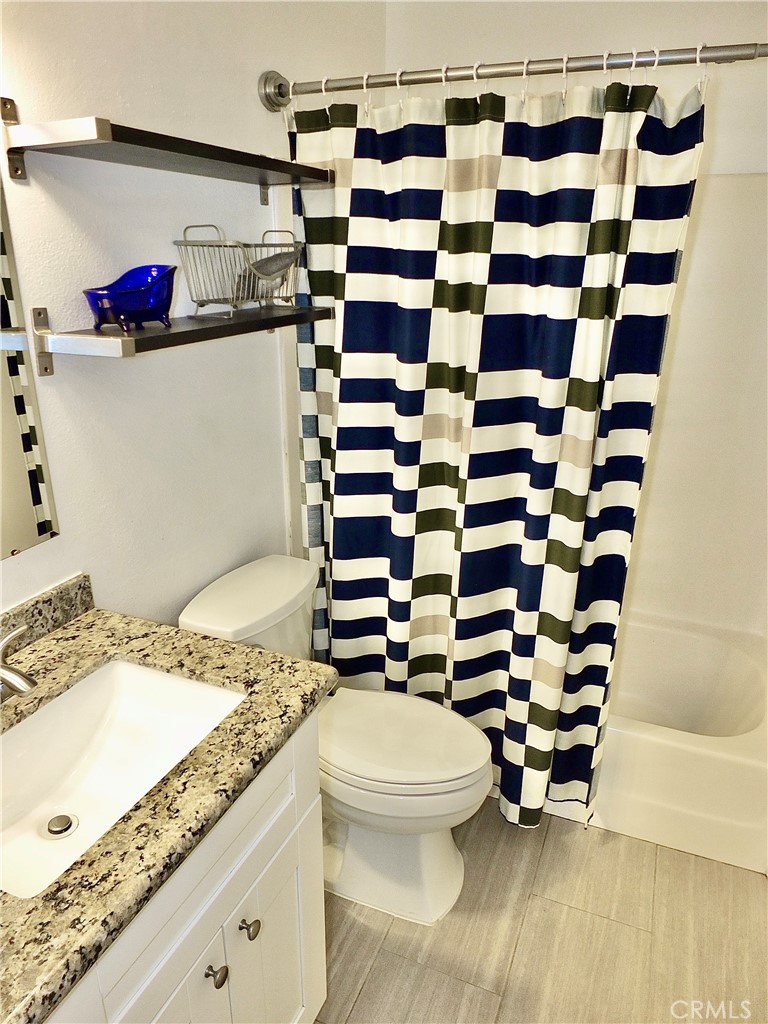 117 West Spring Street, Unit E Long Beach, CA 90806 - Photo 28 of 44 a bathroom with a granite countertop toilet sink and mirror