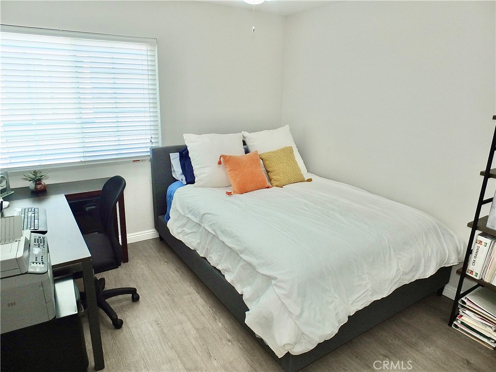 117 West Spring Street, Unit E Long Beach, CA 90806 - Photo 29 of 44 a bedroom with a bed a desk chair and a window
