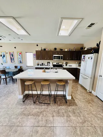 a view of kitchen with stainless steel appliances granite countertop a table chairs sink and cabinets