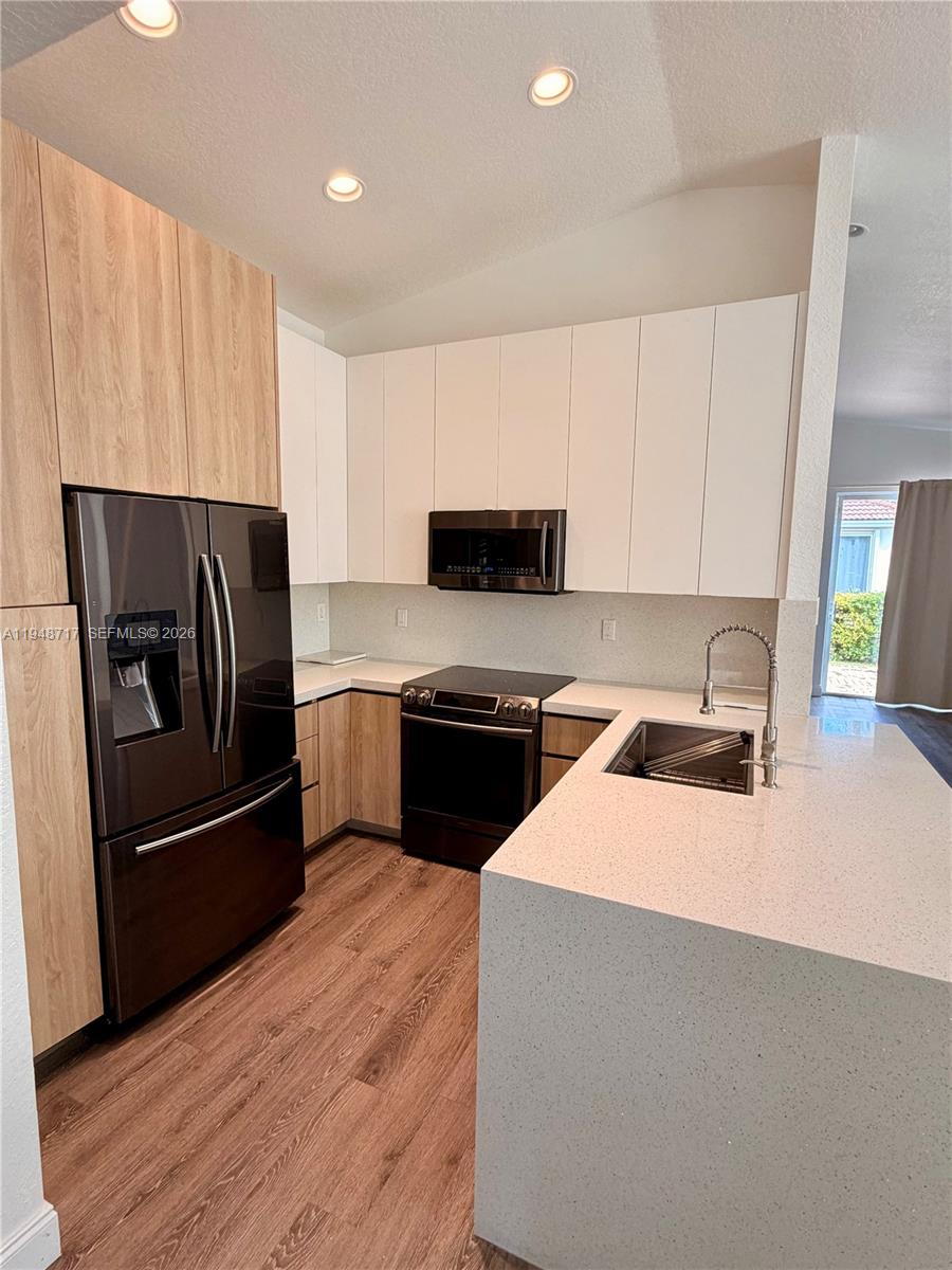18709 Southwest 28th Street Miramar, FL 33029 - Photo 4 of 14 a kitchen with a refrigerator a stove top oven a sink and dishwasher