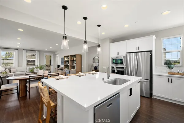 a large kitchen with kitchen island a stove a refrigerator a oven a sink island with a dining table and chairs