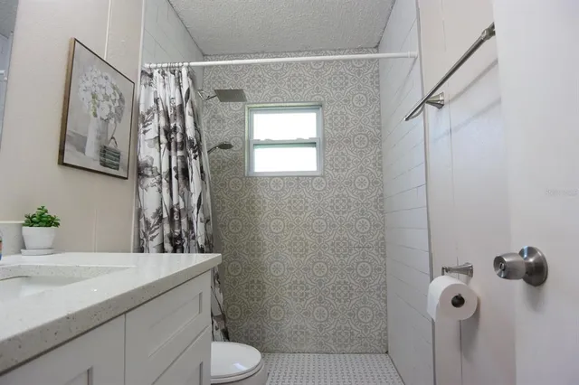 a bathroom with a granite countertop sink a toilet and shower