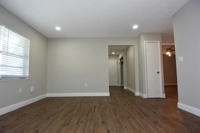 an empty room with wooden floor and windows